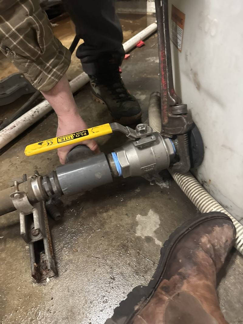 Stainless ball valve being tightened with a pipe wrench on a drain line