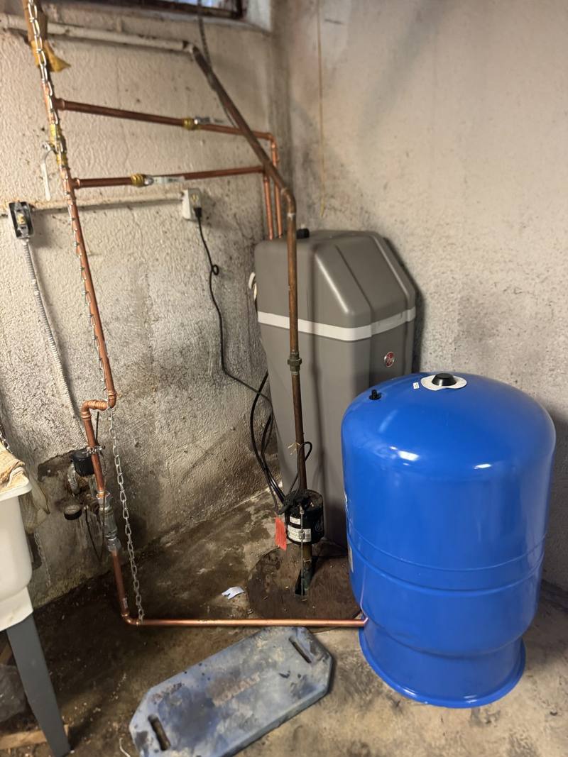 Water softener, blue pressure tank and new copper piping in a basement